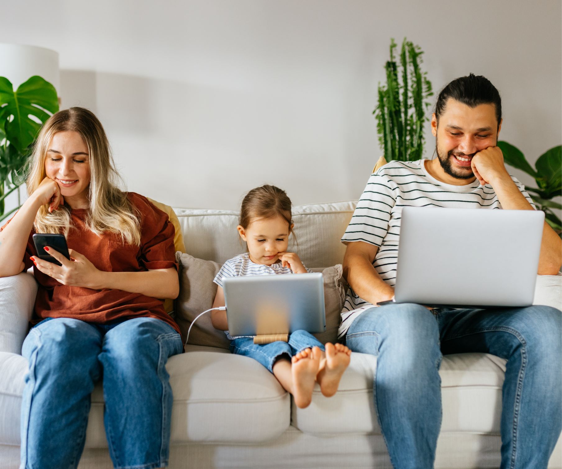 Ģimene uz dīvāna laimīgi skatās datorā