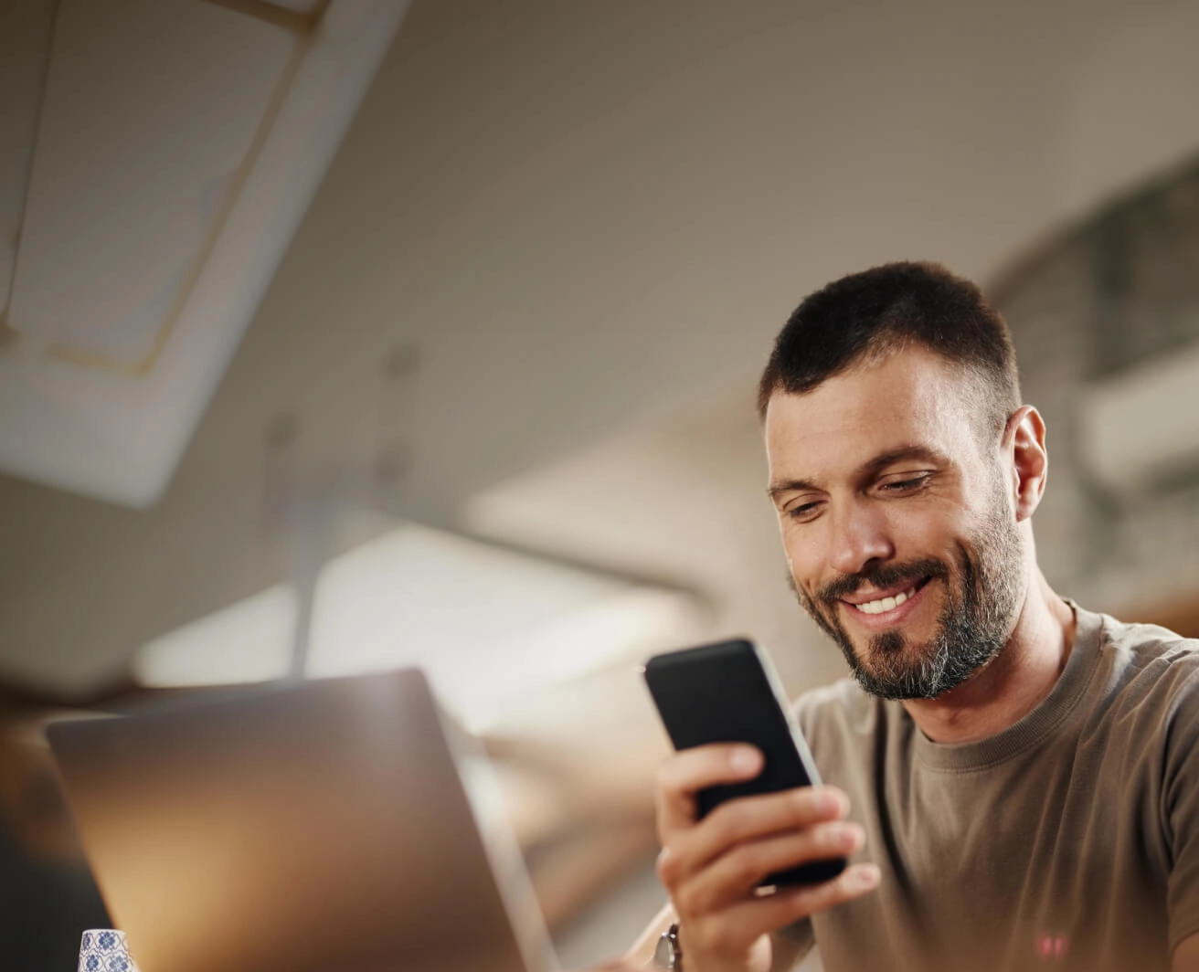 Vīrietis skatās telefonā un smaida