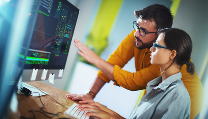 Divi kolēģi pie monitoriem kopā pārskata kodu