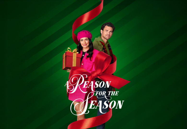 Sieviete un vīrietis uz zaļa fona ar lielu sarkanu lenti. Sieviete tur dāvanu kastīti, apakšā teksts 'A Reason for the Season'.
