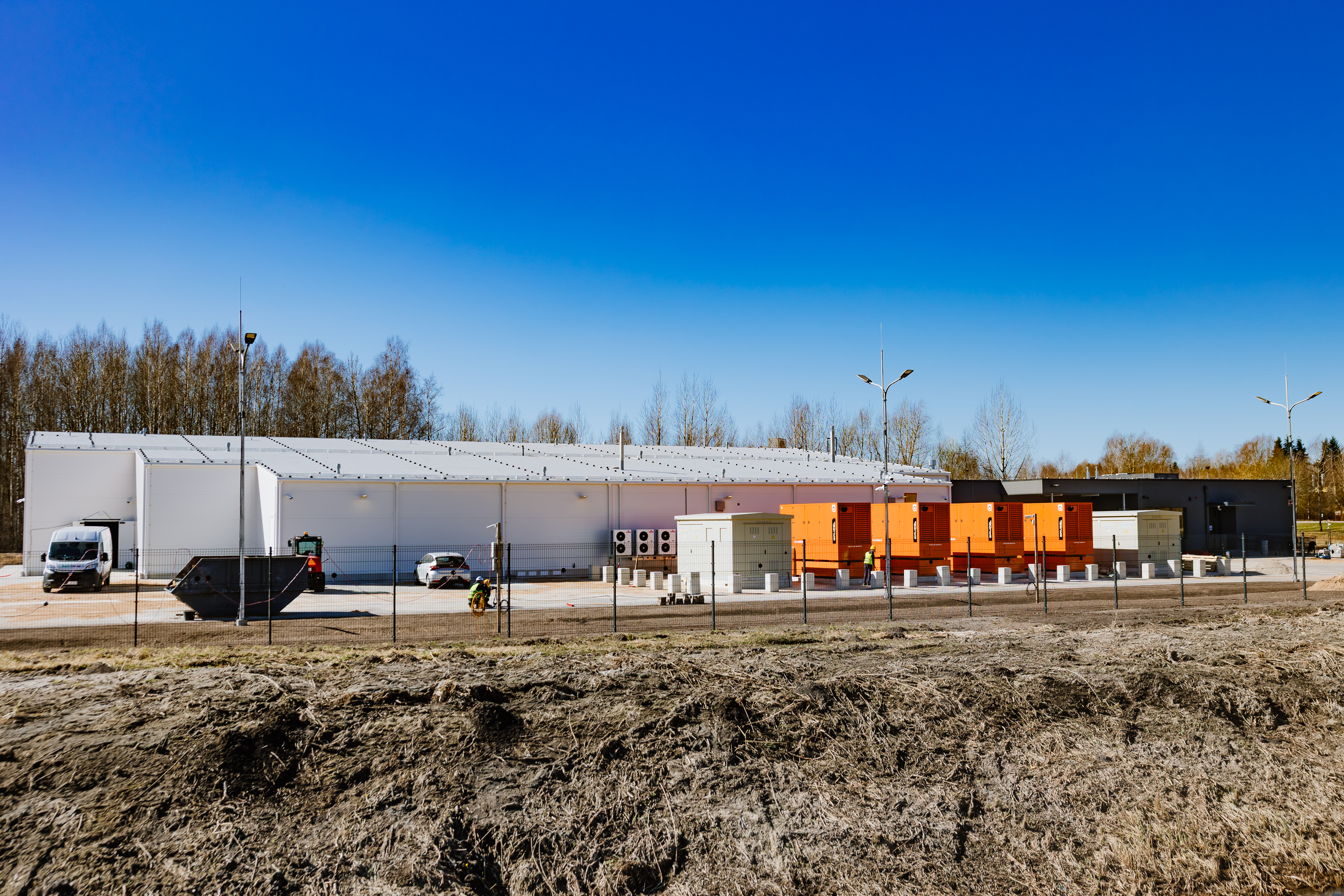Datu centra ēkas ārskats ar tehniskajām iekārtām un teritoriju saulainā dienā