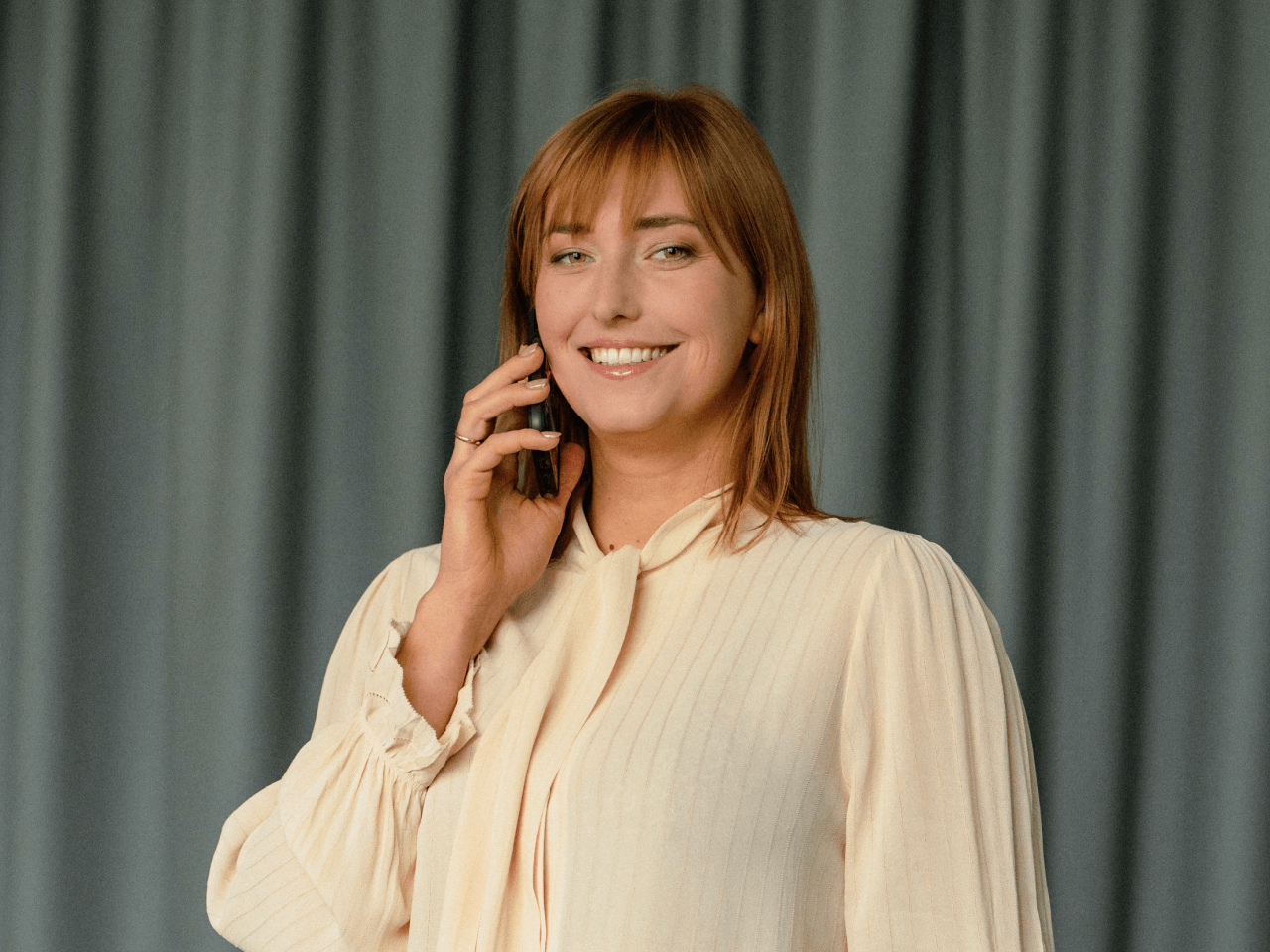 sieviete skatās kamerā, kamēr runā pa telefonu