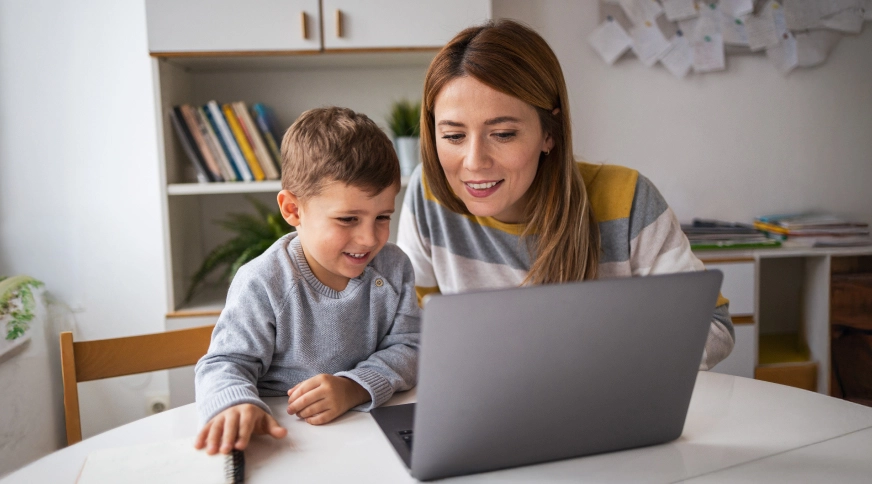 Mamma ar dēlu laimīgi skatās portatīvajā datorā