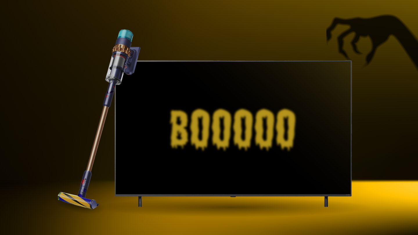 Bezvadu putekļsūcējs atbalstīts pret televizoru ar spocīgu uzrakstu “BOOOOO”; augšējā stūrī rokas ēna.