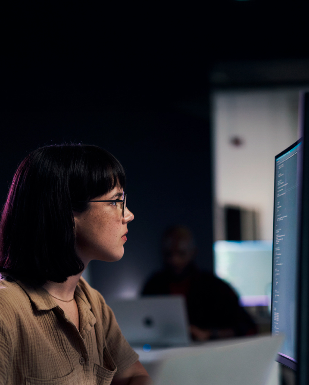 Cilvēks strādā pie koda tumšā birojā