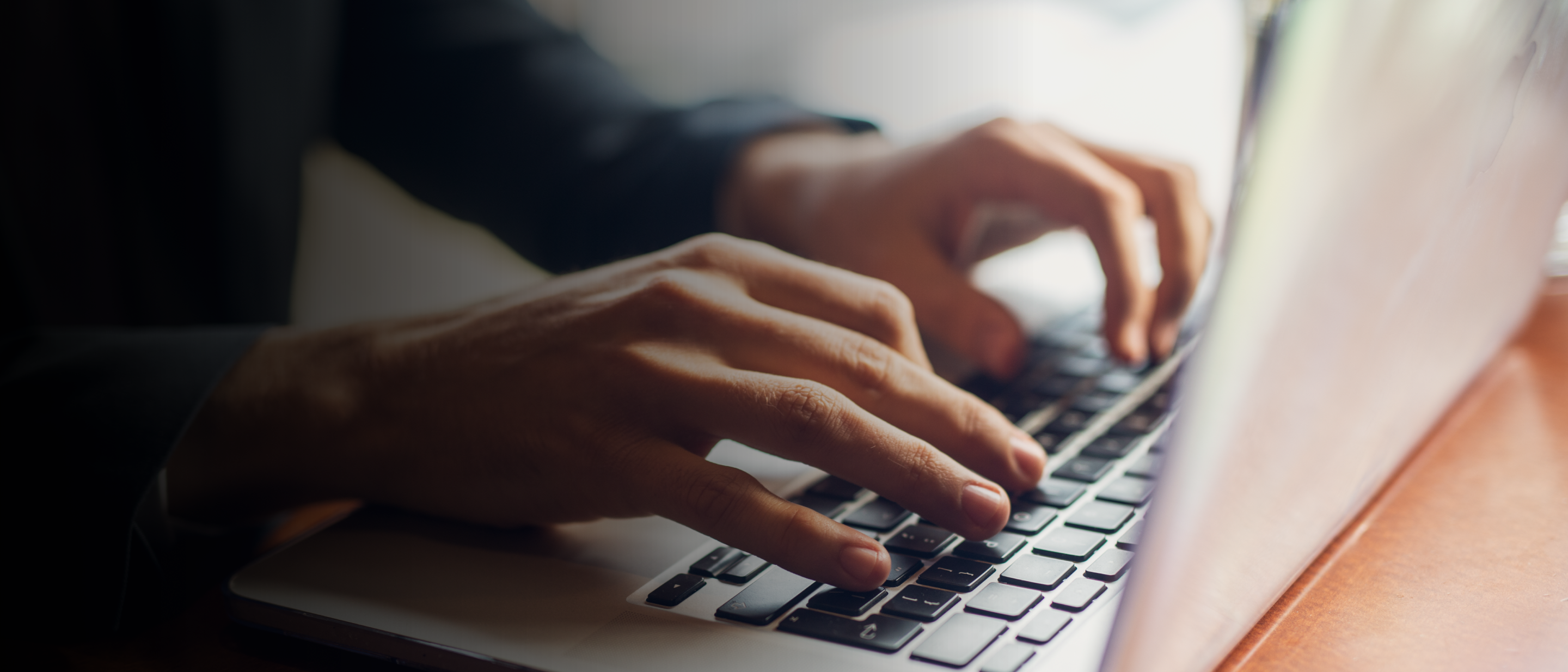 Tuvplāns: rokas raksta uz klēpjdatora tastatūras uz koka galda.