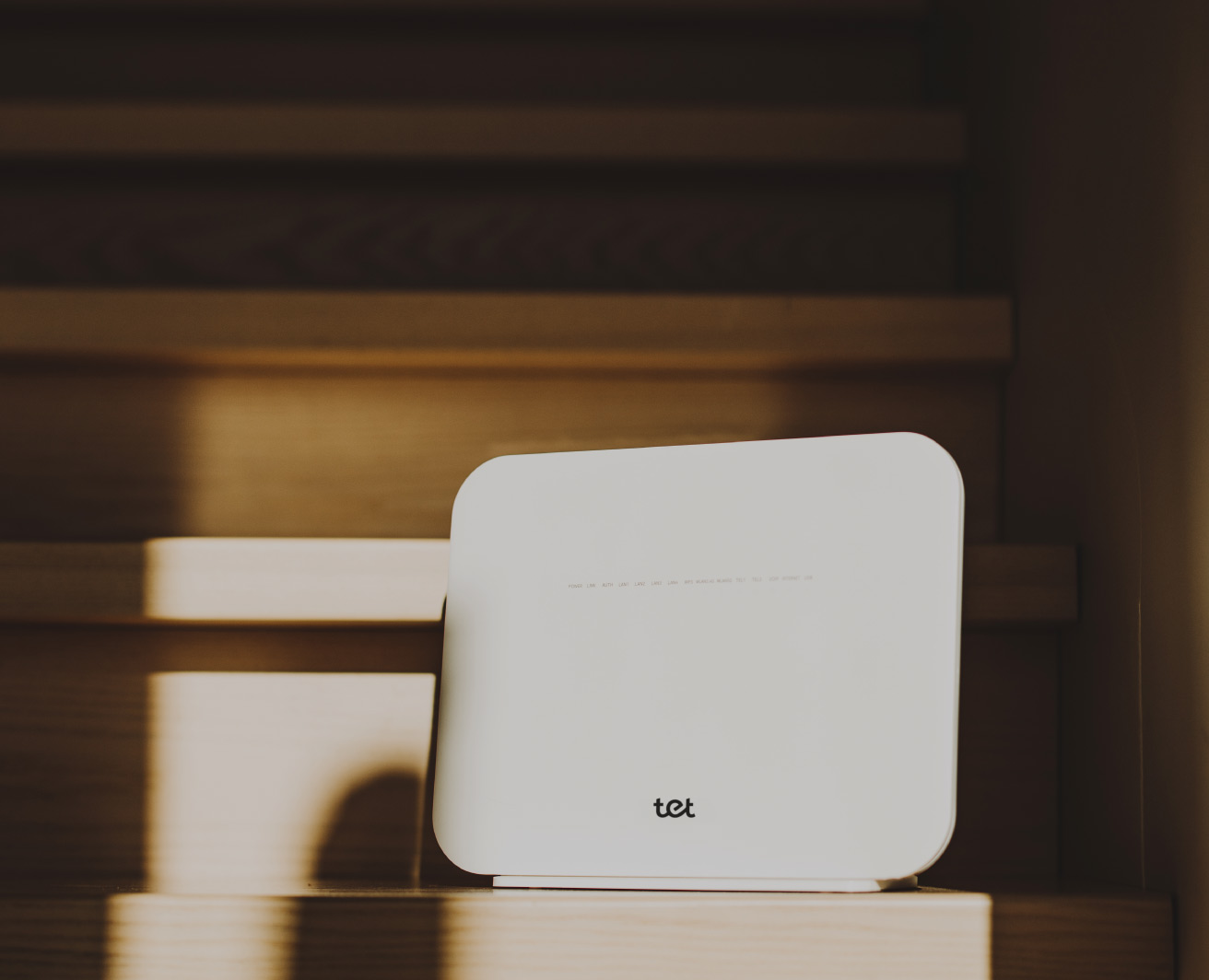 Balts Tet Wi‑Fi maršrutētājs uz koka kāpnēm.