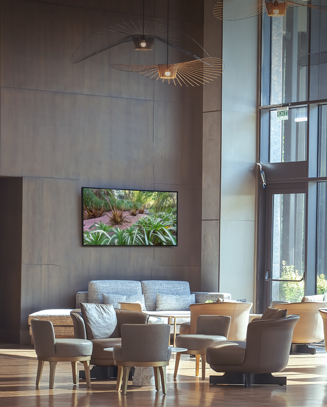 Mūsdienīga atpūtas zona ar sēdvietām un sienas TV, ekrānā redzama dabas aina.