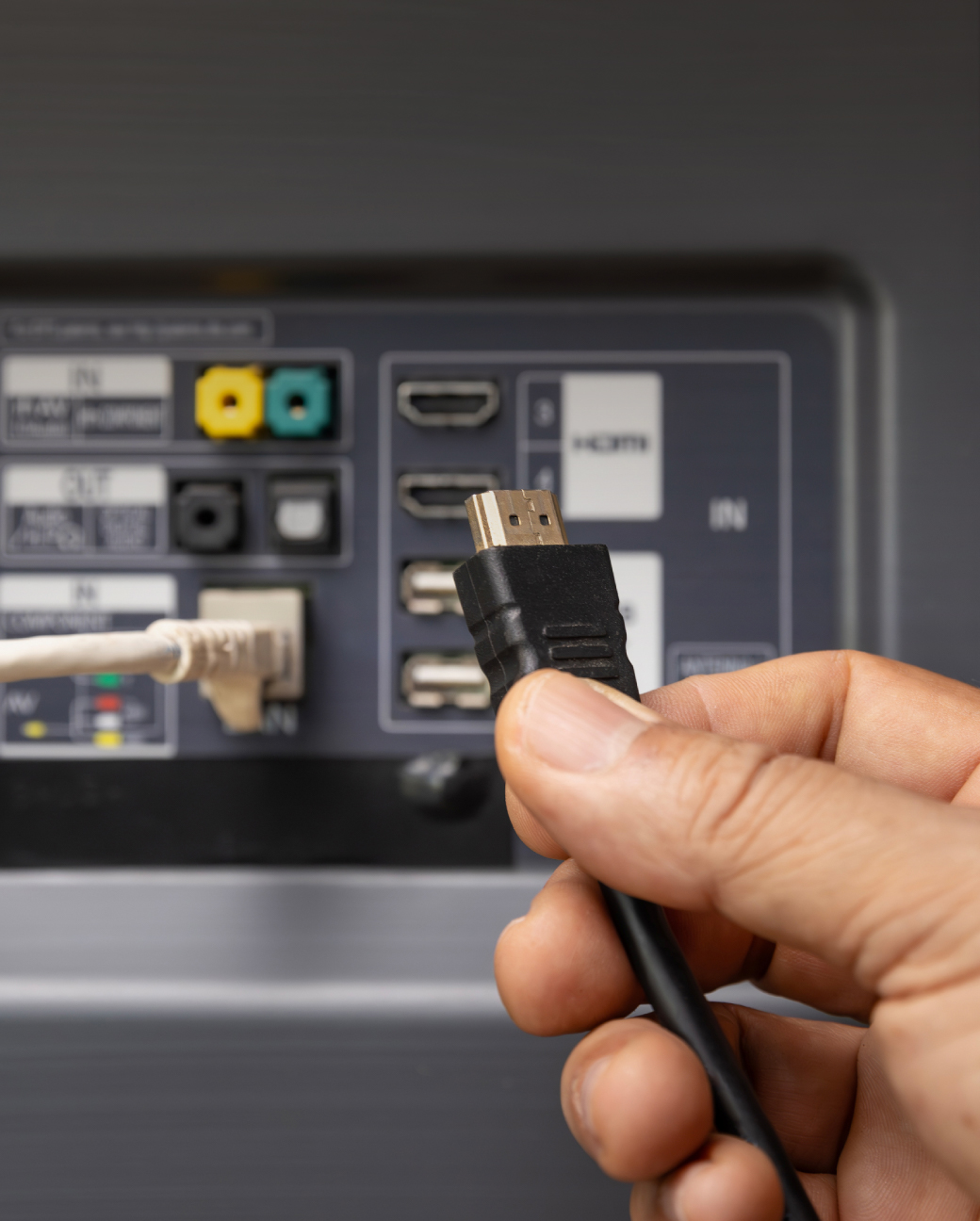 Roka pievieno HDMI kabeli televizora aizmugurē.