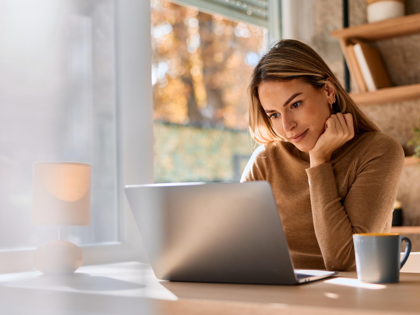 Priecīgs kungs ar brillēm skatās viedtālrunī un sveicina kameru.